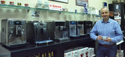 Luciano Iarusso, Owner of Espresso Machine Experts standing in front of superautomatic espresso machines in his store